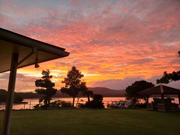 *【幻想的な夕焼け】山に沈む夕日が空を赤く染め、海までもがその美しさを映し出す非現実的な光景です。