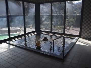 *大浴場一例／大きな窓から森林浴気分を味わえます。春は桜の花見も楽しめる。